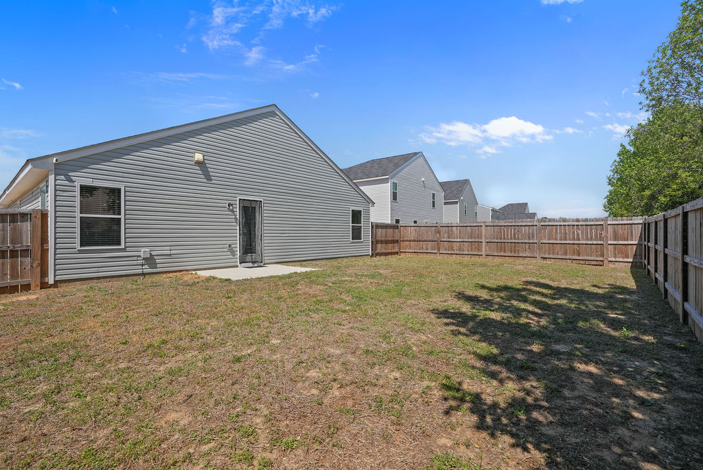 Fully fenced backyard of single-story home in Kirwin Village, Raeford NC, with concrete patio and rear exterior view