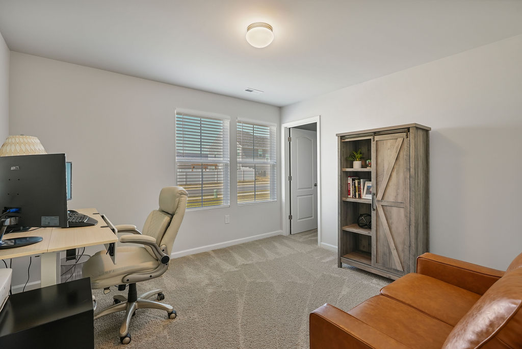 Carpeted bedroom in single-story home near Fort Bragg in Raeford NC, shown with home office setup and natural window light
