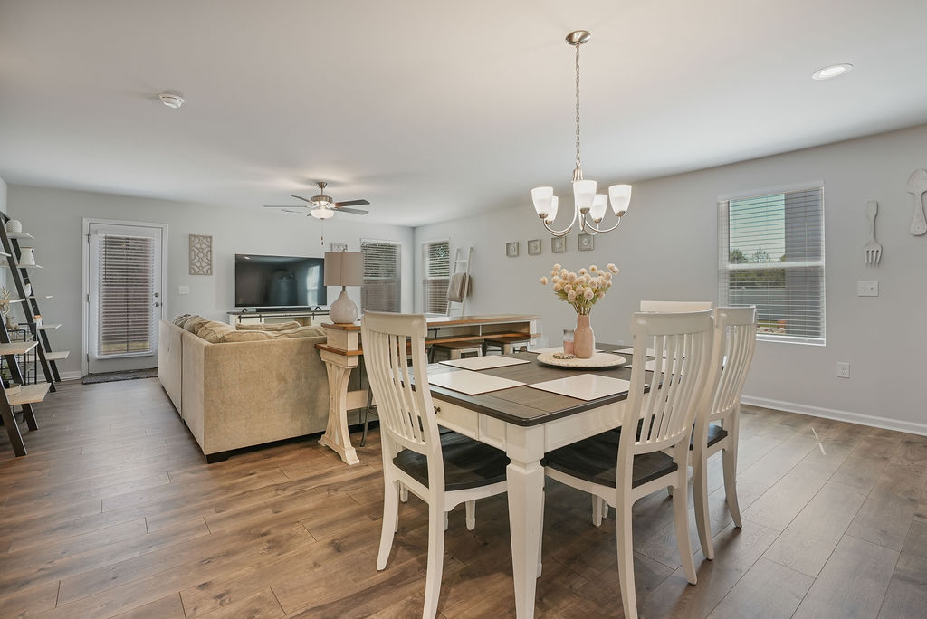 Open dining area with chandelier, laminate flooring, and open view to living room with ceiling fan in single-story home at 250 Melbourne Dr, Raeford NC