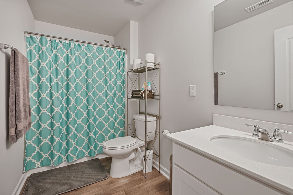 Full bathroom with tub and shower, single vanity with white countertop, and laminate flooring in 2024-built home in Raeford NC near Fort Bragg