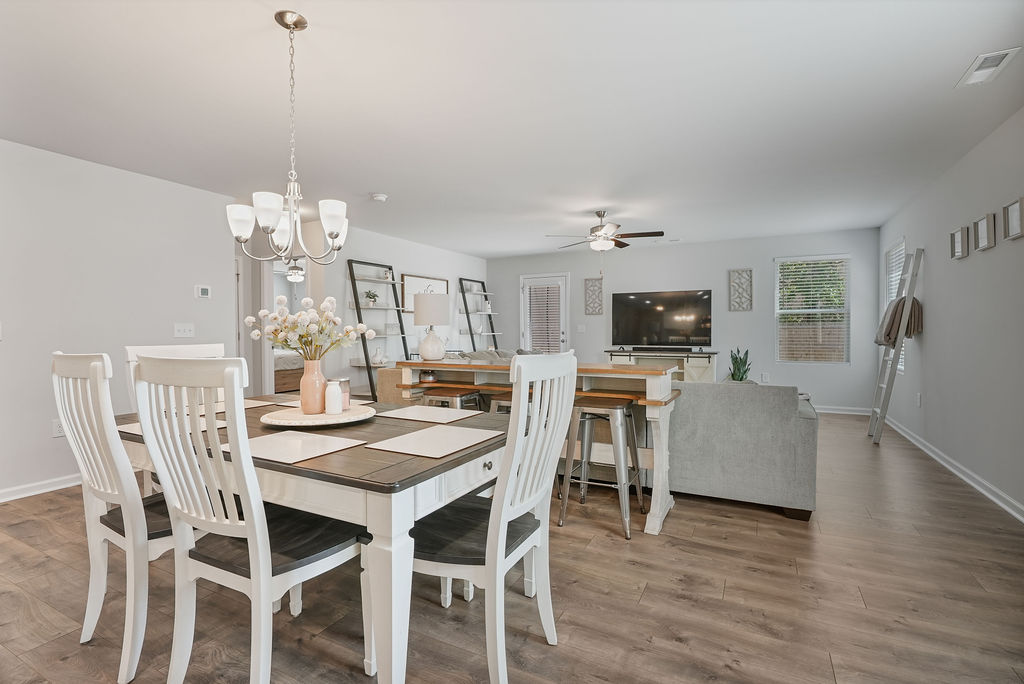 Dining and living room open floor plan with laminate flooring, ceiling fan, and natural light from multiple windows in single-story home near Fort Bragg in Raeford NC