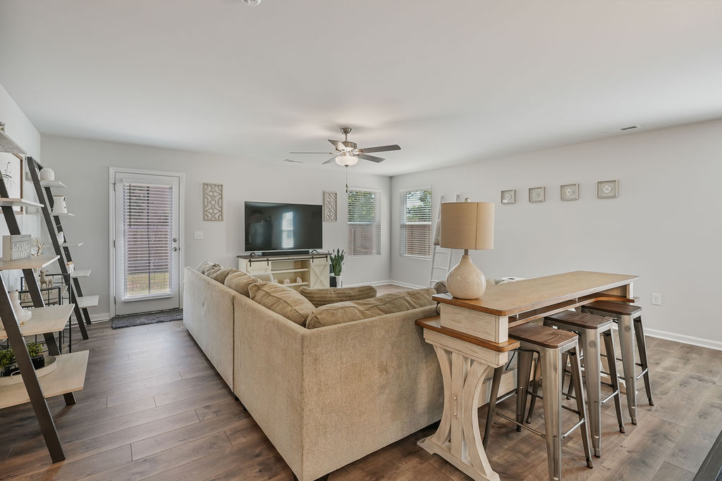 Living room with laminate flooring, ceiling fan, and back door access in open-concept single-story home at 250 Melbourne Dr, Raeford NC near Fort Bragg