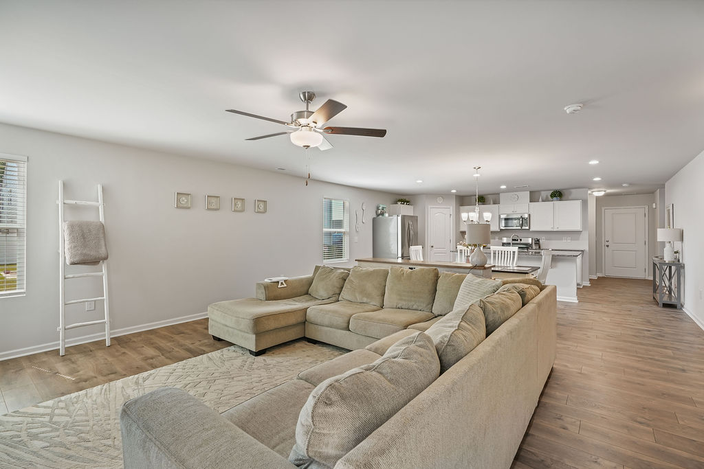 Wide view of living room and open kitchen with laminate flooring, ceiling fan, recessed lighting, and stainless steel appliances in 2024-built home at 250 Melbourne Dr, Raeford NC