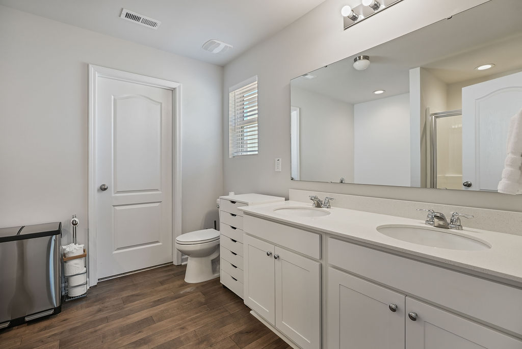 Primary bathroom with double vanity, white countertop, large mirror, laminate flooring, and walk-in closet access in single-story home at 250 Melbourne Dr, Raeford NC