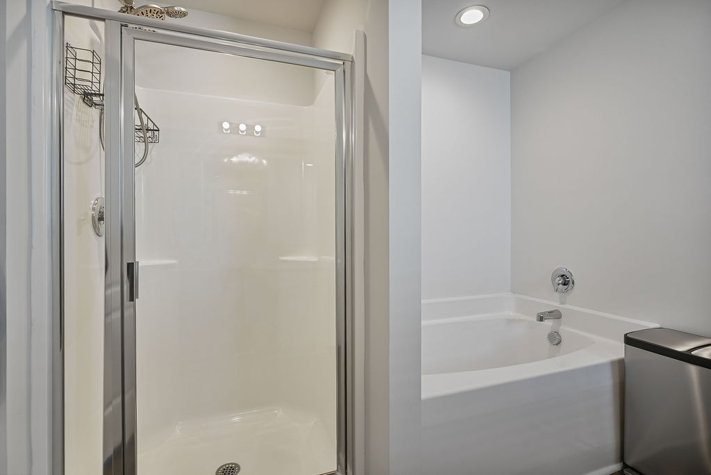 Primary bathroom showing separate walk-in shower with glass door and garden tub in single-story home near Fort Bragg in Raeford NC